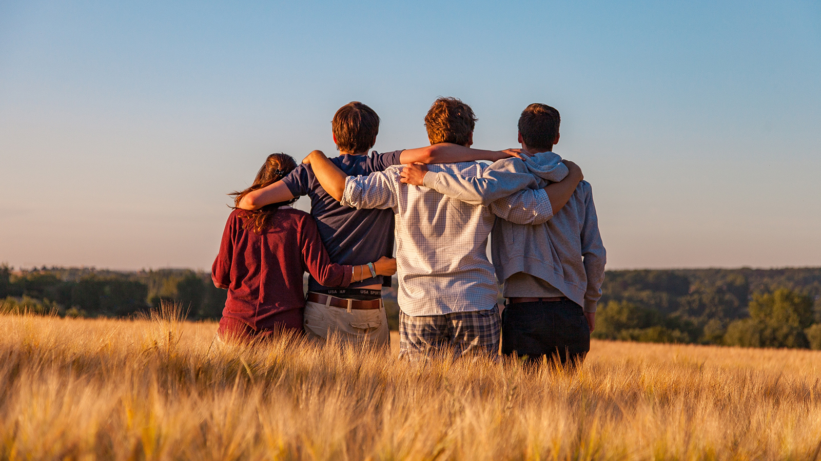 Friends hanging out in a field, seen from behind.
