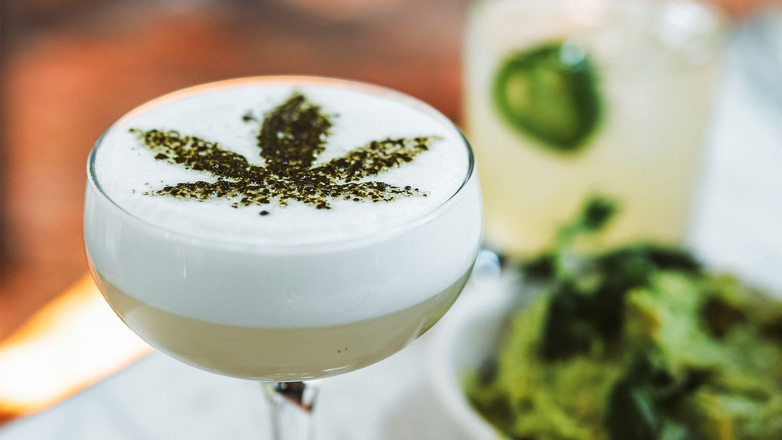 A refreshing drink with minced herbs sprinkled on top in the shape of a marijuana leaf.